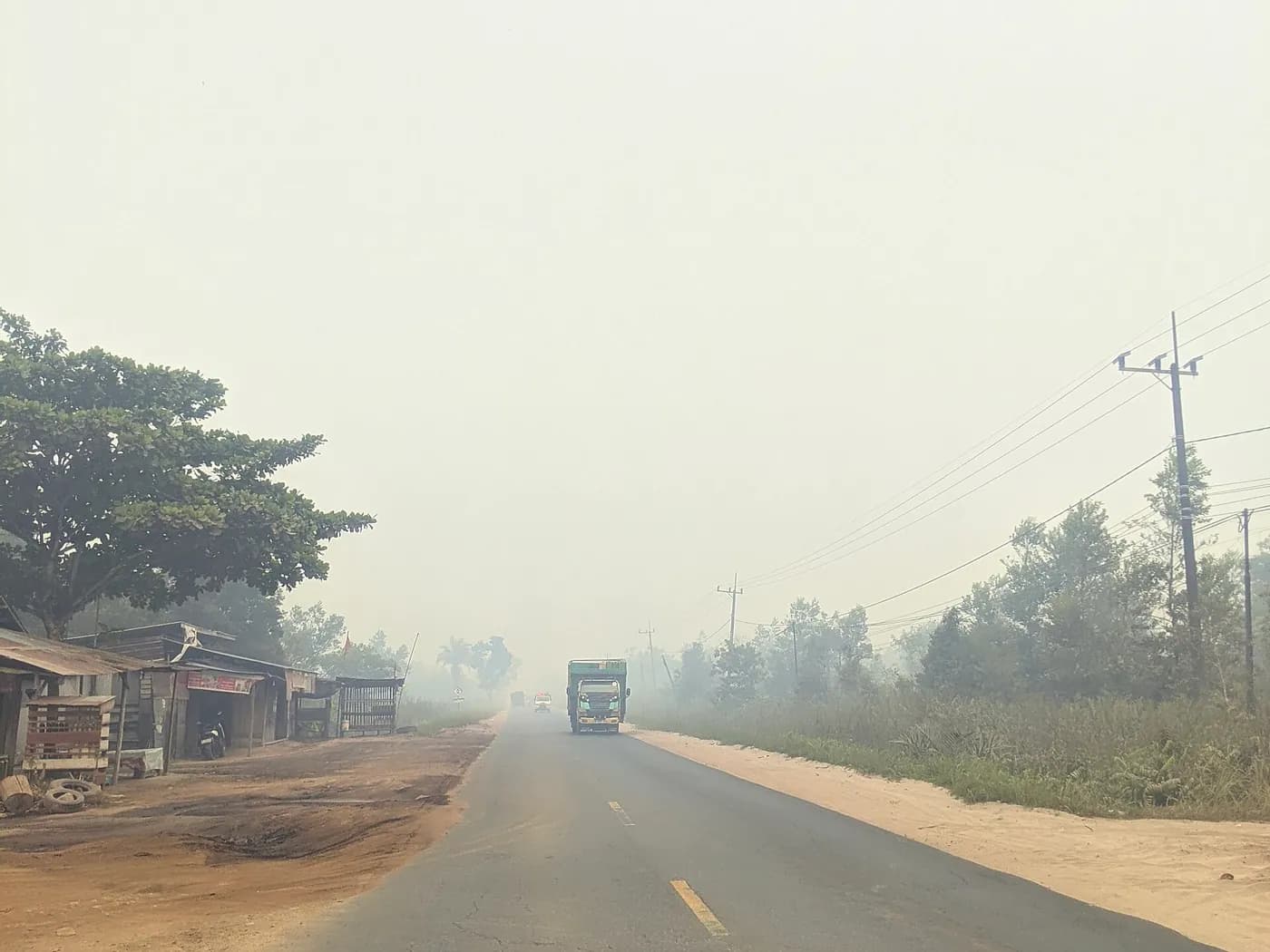 Truk melaju di jalan yang diselimuti kabut asap tebal di Palangka Raya